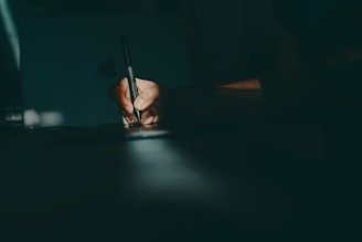 a person writing on a piece of paper with a pen