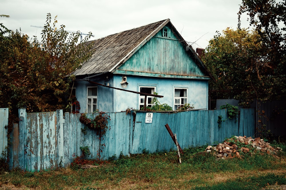 a blue house with a wooden fence around it
