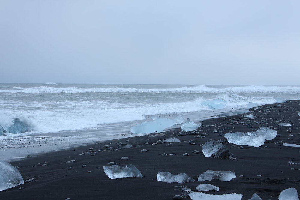 a beach covered in lots of ice next to the ocean
