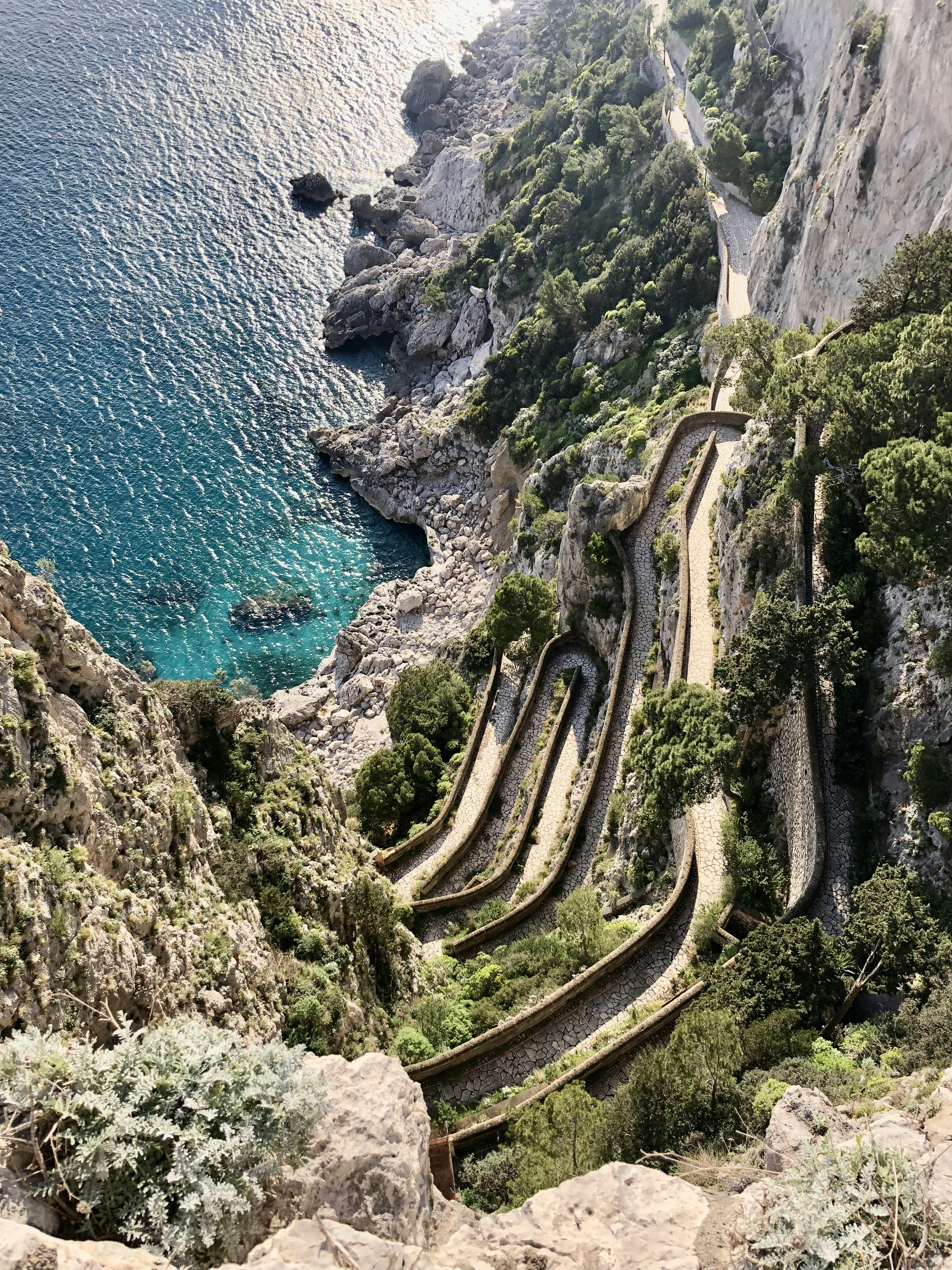 a scenic view of a winding road next to a body of water