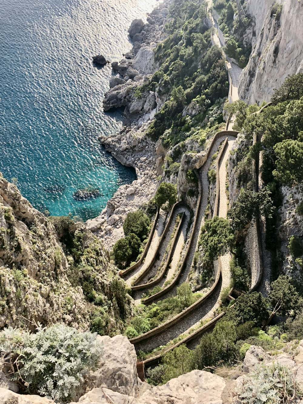 a scenic view of a winding road next to a body of water