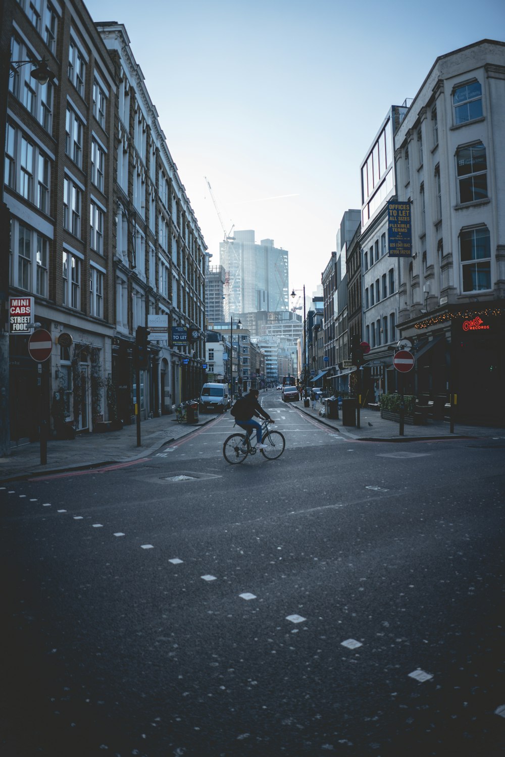 a man riding a bike down a street next to tall buildings