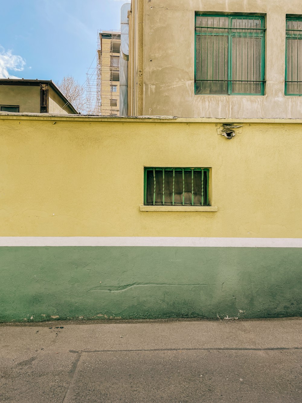 a yellow building with a green window and a red fire hydrant