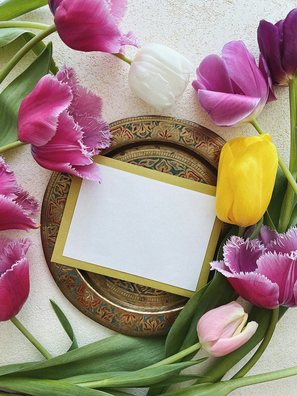 a plate with a blank card surrounded by flowers