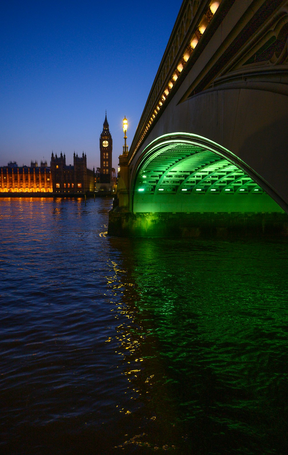 a bridge over a body of water with a clock tower in the background