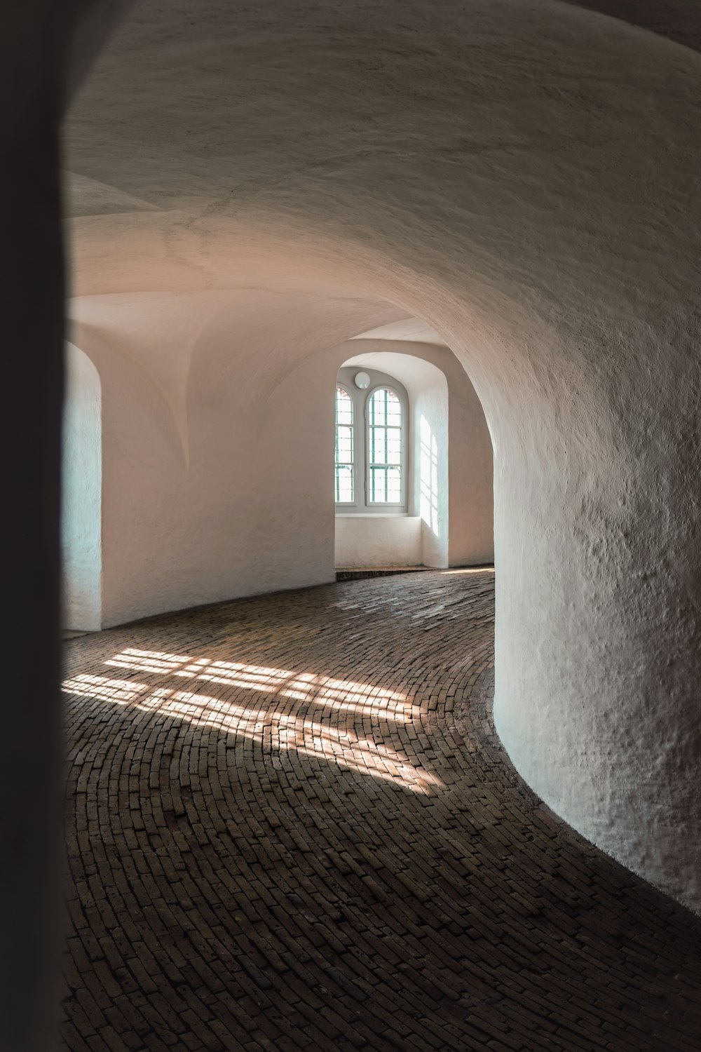 a room with a brick floor and arched windows