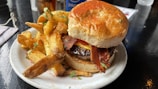 A vibrant shot of a cheeseburger with crispy bacon and tomato slices, served with golden fries.