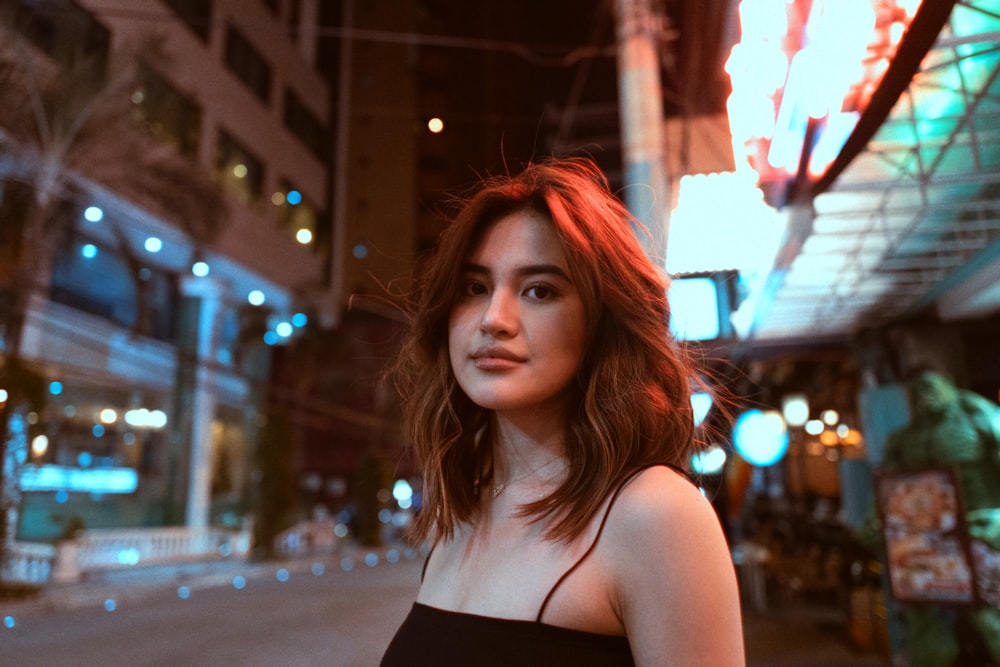 a woman in a black dress standing on a city street