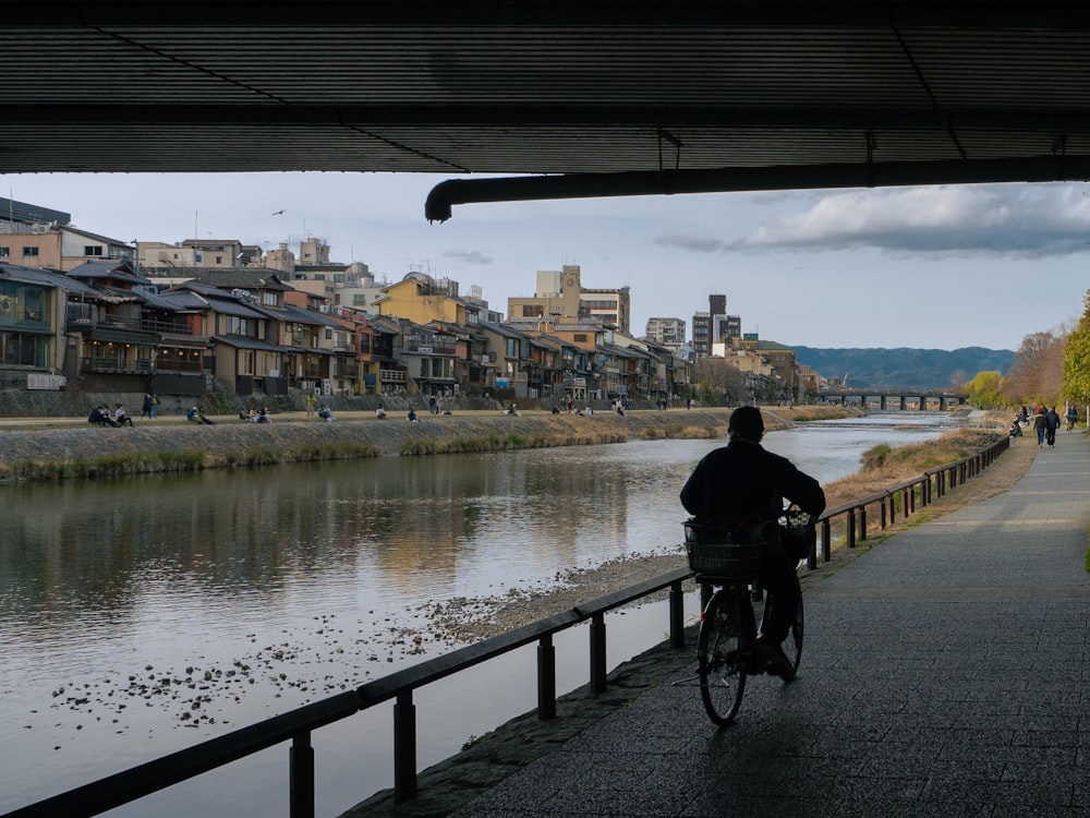 a man riding a bike down a street next to a river