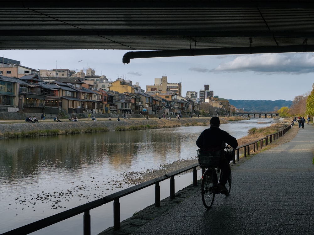 um homem andando de bicicleta por uma rua ao lado de um rio