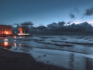 A stunning twilight shot of a luxury beachside resort with golden lights reflecting on calm waters.