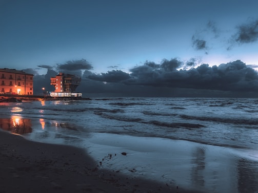 A stunning twilight shot of a luxury beachside resort with golden lights reflecting on calm waters.