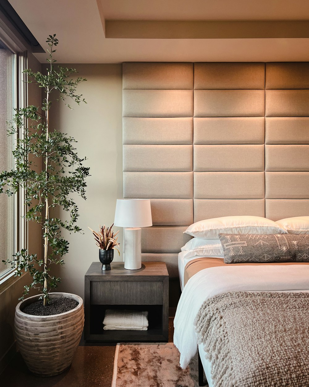 a bed sitting next to a window with a plant on top of it