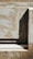 A textured surface with a mix of rough and smooth areas, showing a combination of light and shadow. The surface appears to be made of wood or a similar material with visible grains and markings, and a solid geometric shape casts a shadow across the surface.