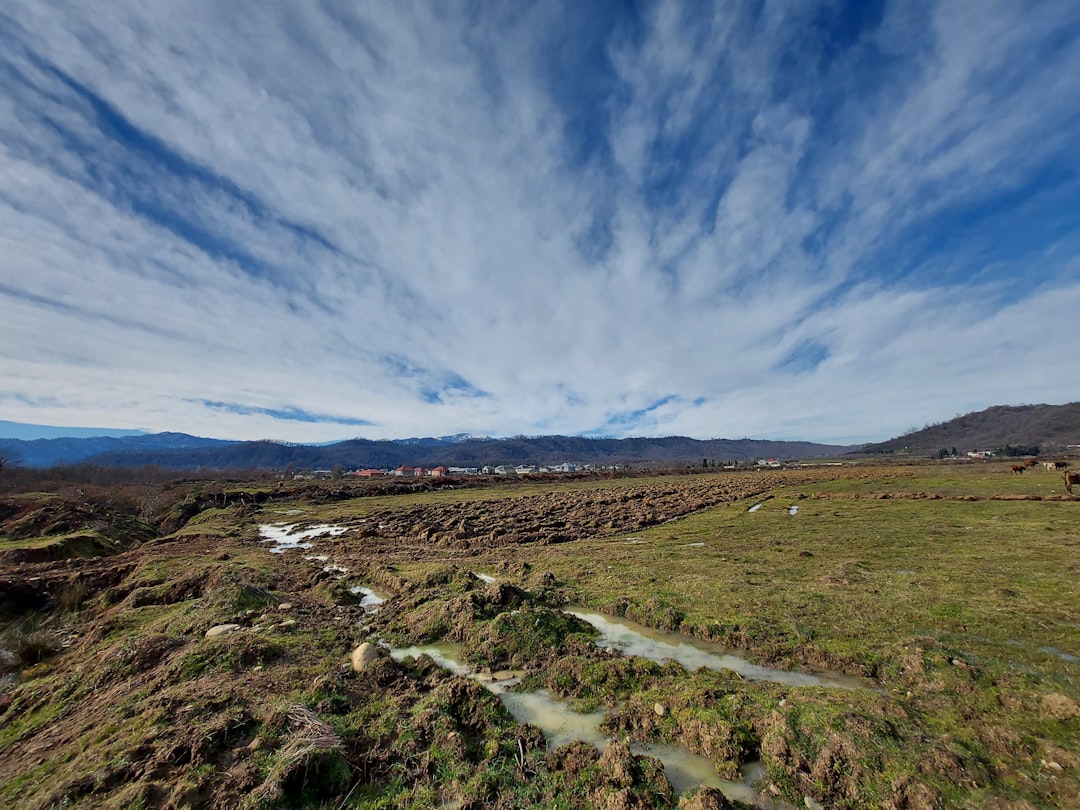 a wide open field with a stream running through it,