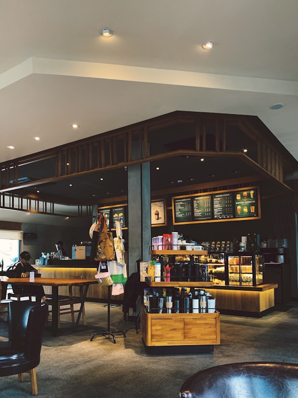 A cozy coffee shop interior with a variety of coffee drinks displayed on a wooden counter.