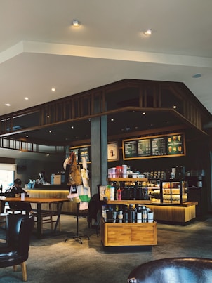 A cozy coffee shop interior with a variety of coffee drinks displayed on a wooden counter.