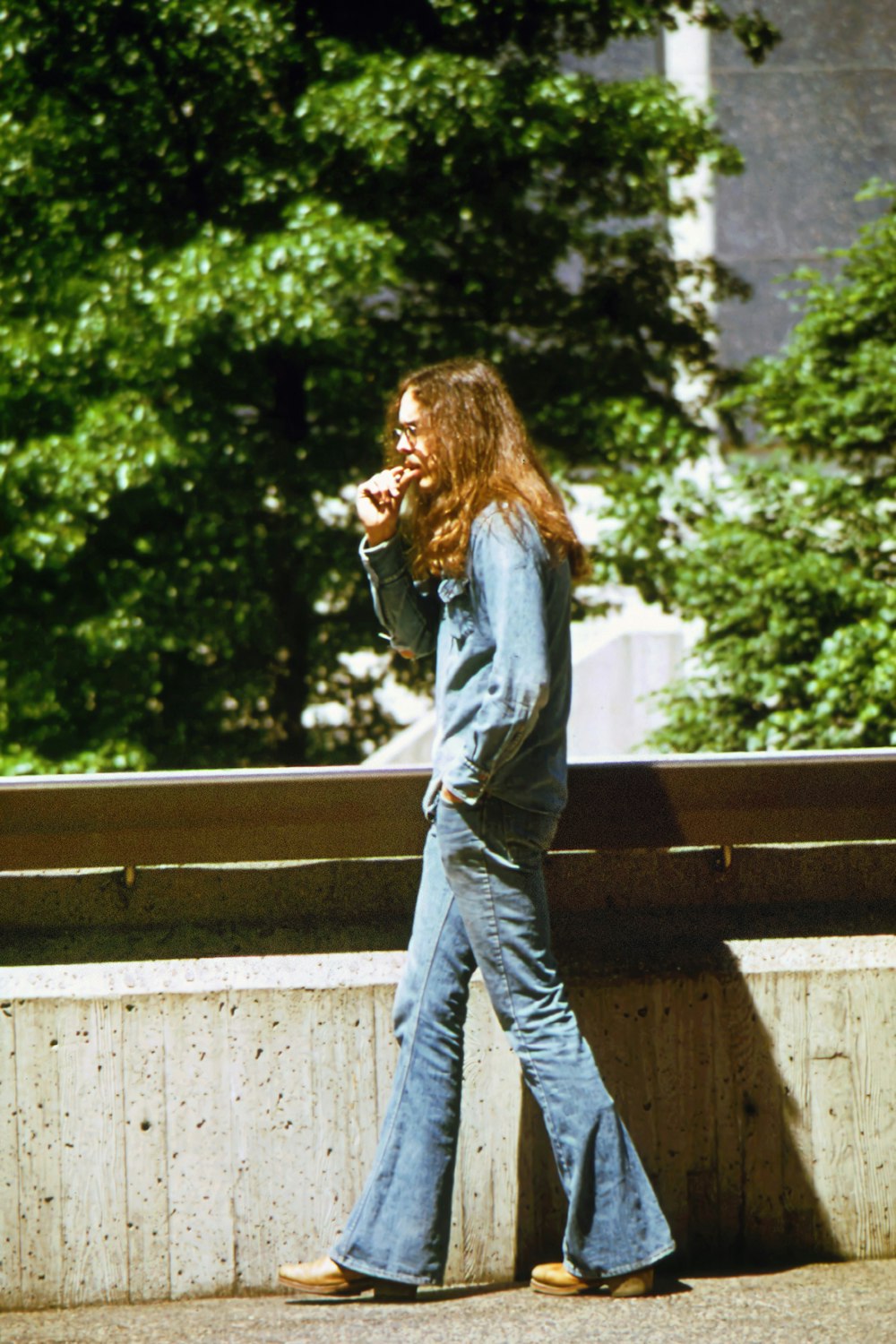 a woman with long hair walking down a sidewalk