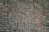 A wall featuring numerous phrases in various languages, including 'I love you,' written in white script on dark tiles. Red heart shapes accent certain sections, creating a romantic theme.