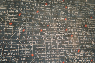 A wall featuring numerous phrases in various languages, including 'I love you,' written in white script on dark tiles. Red heart shapes accent certain sections, creating a romantic theme.