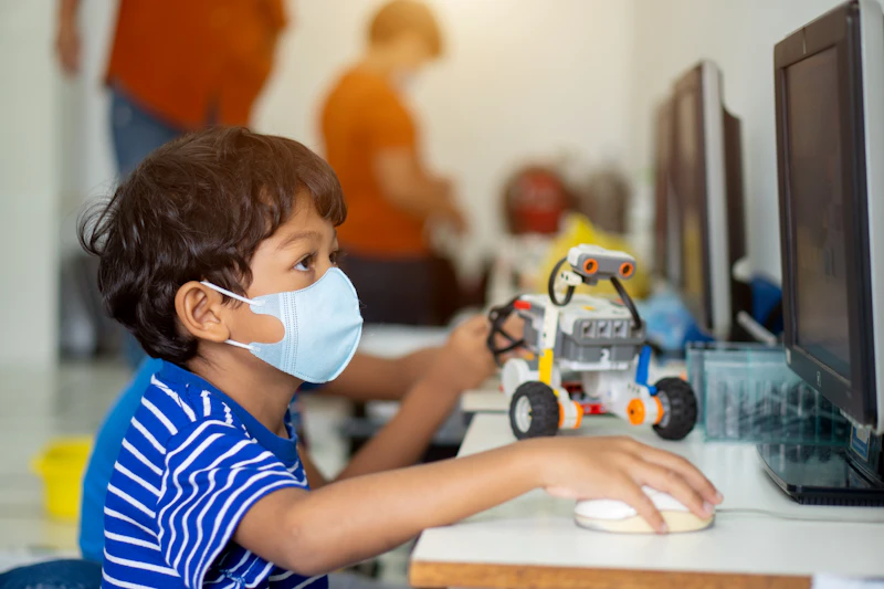 A child proudly holding up a robot they built in class