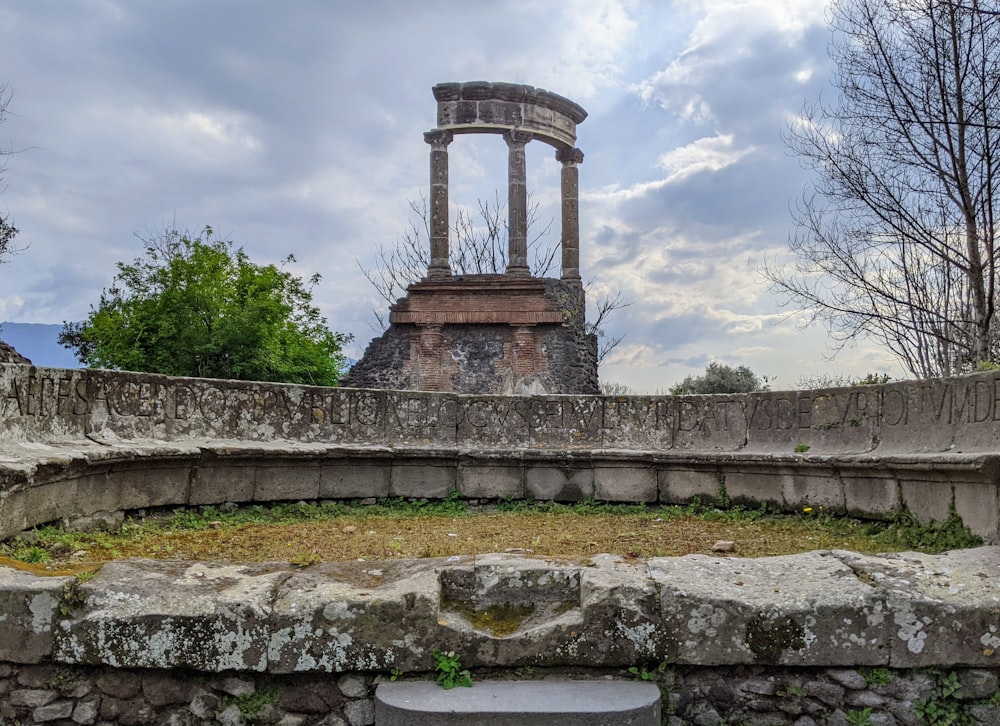 a stone structure with a clock tower in the background