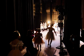 A vibrant backstage scene with models and performers preparing under warm lights.