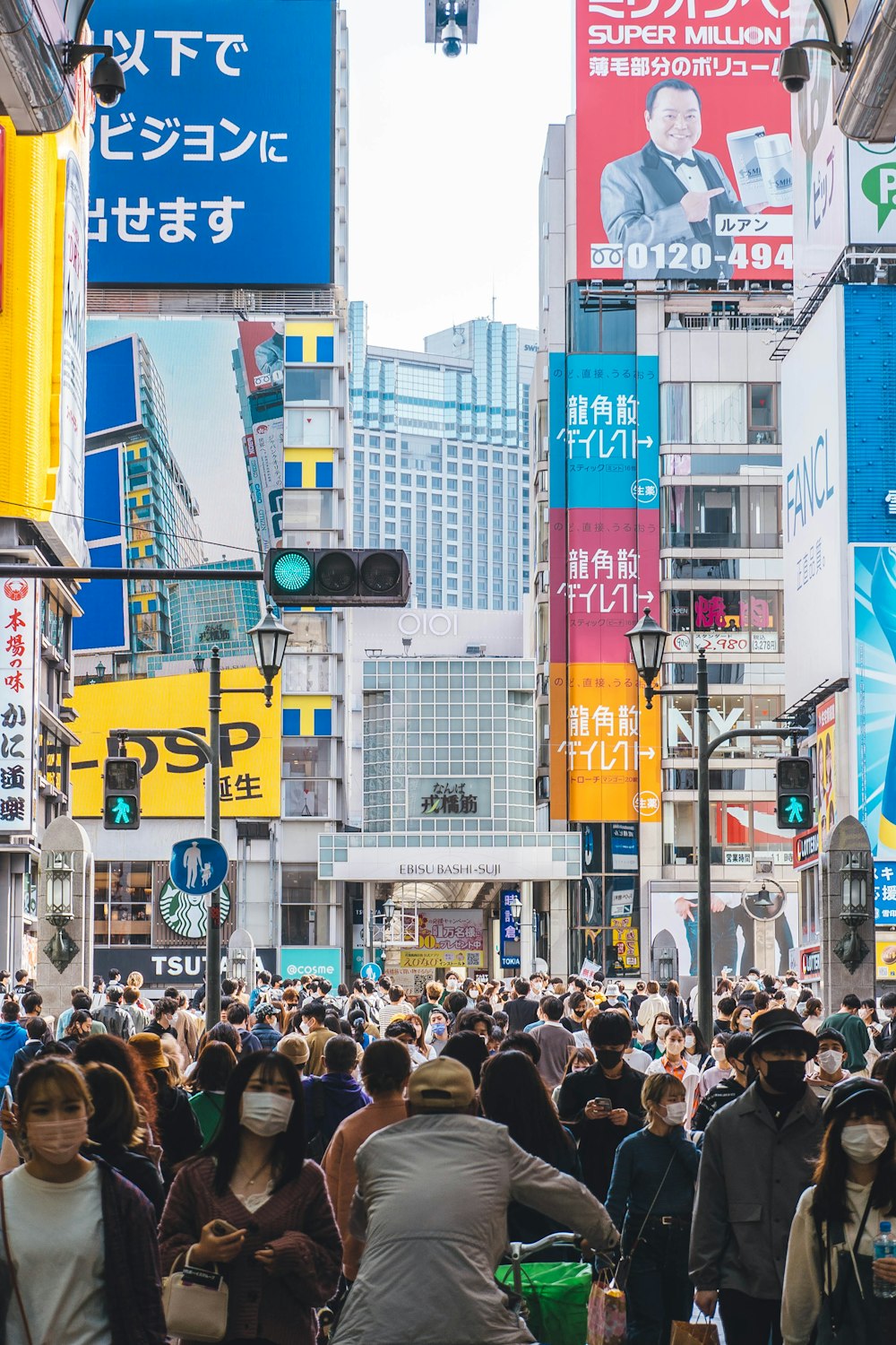 a crowd of people walking down a street next to tall buildings