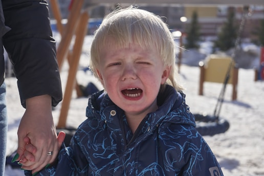 a little boy crying while holding his hand