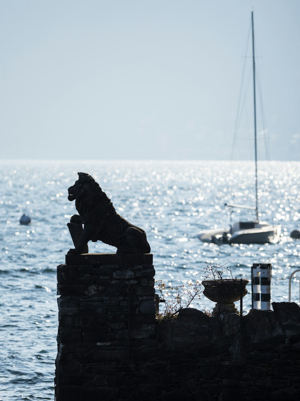 una estatua de un león sentado encima de un muro de piedra