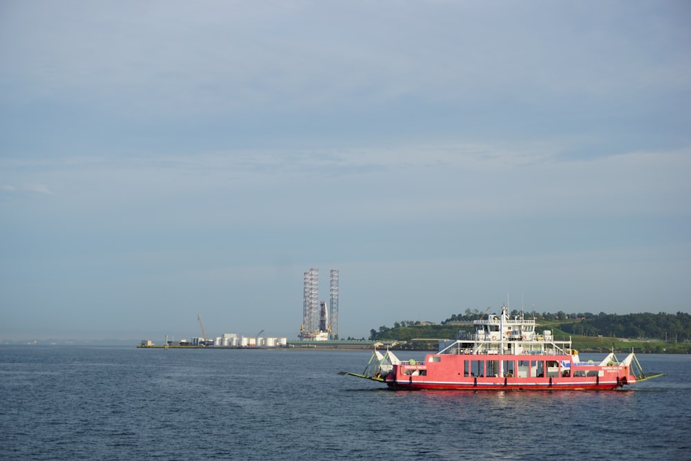 a large red boat floating on top of a large body of water