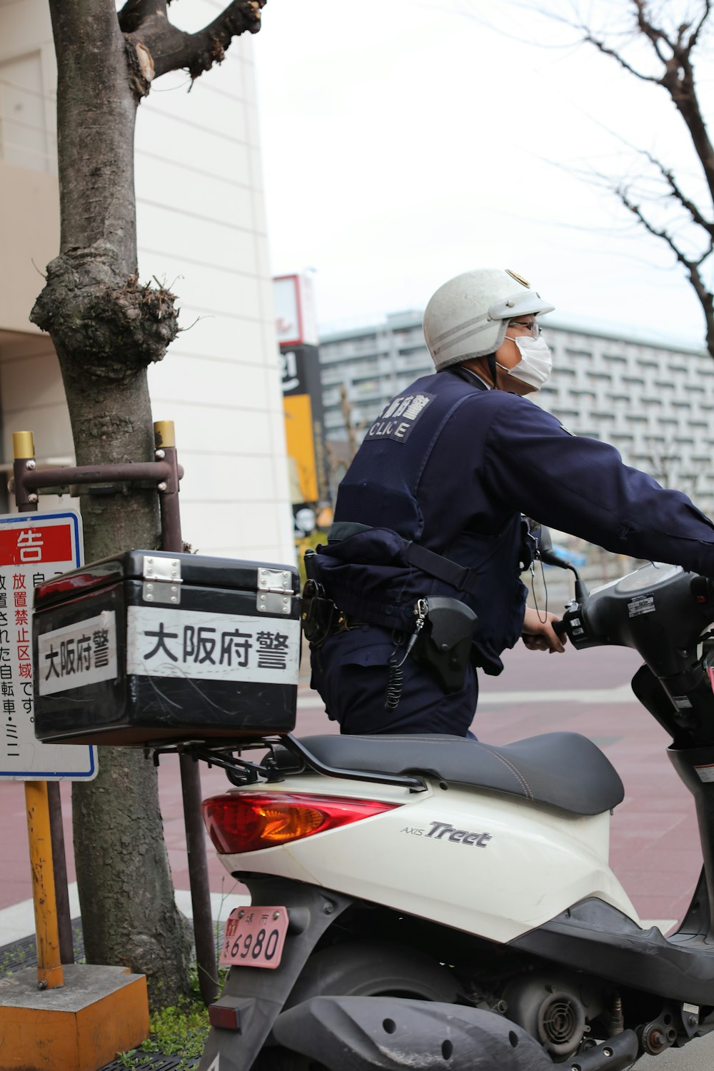 a man riding a motorcycle down a street next to a tree