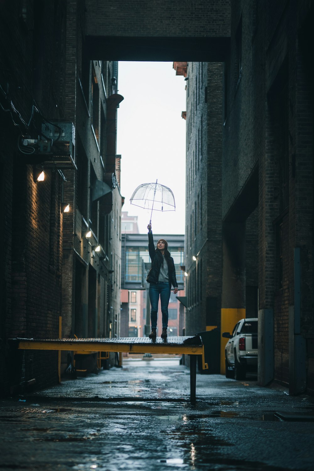 a woman holding an umbrella standing in an alleyway