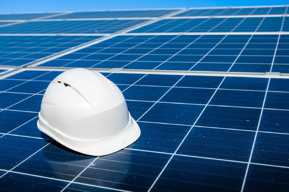 a white hard hat sitting on top of a solar panel