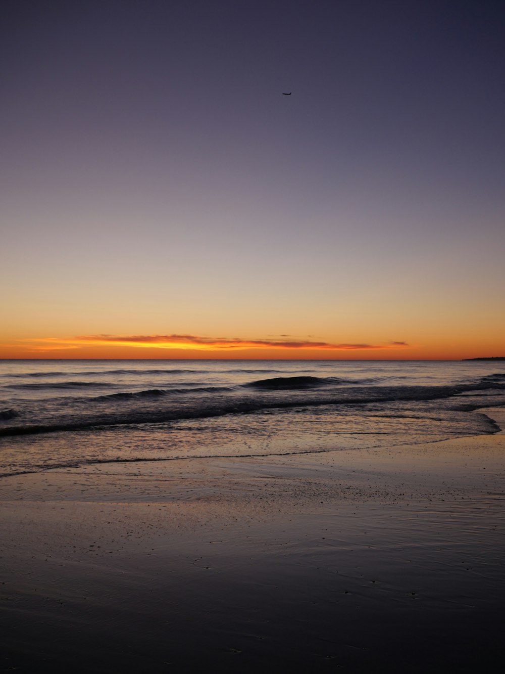 the sun is setting over the ocean and the beach