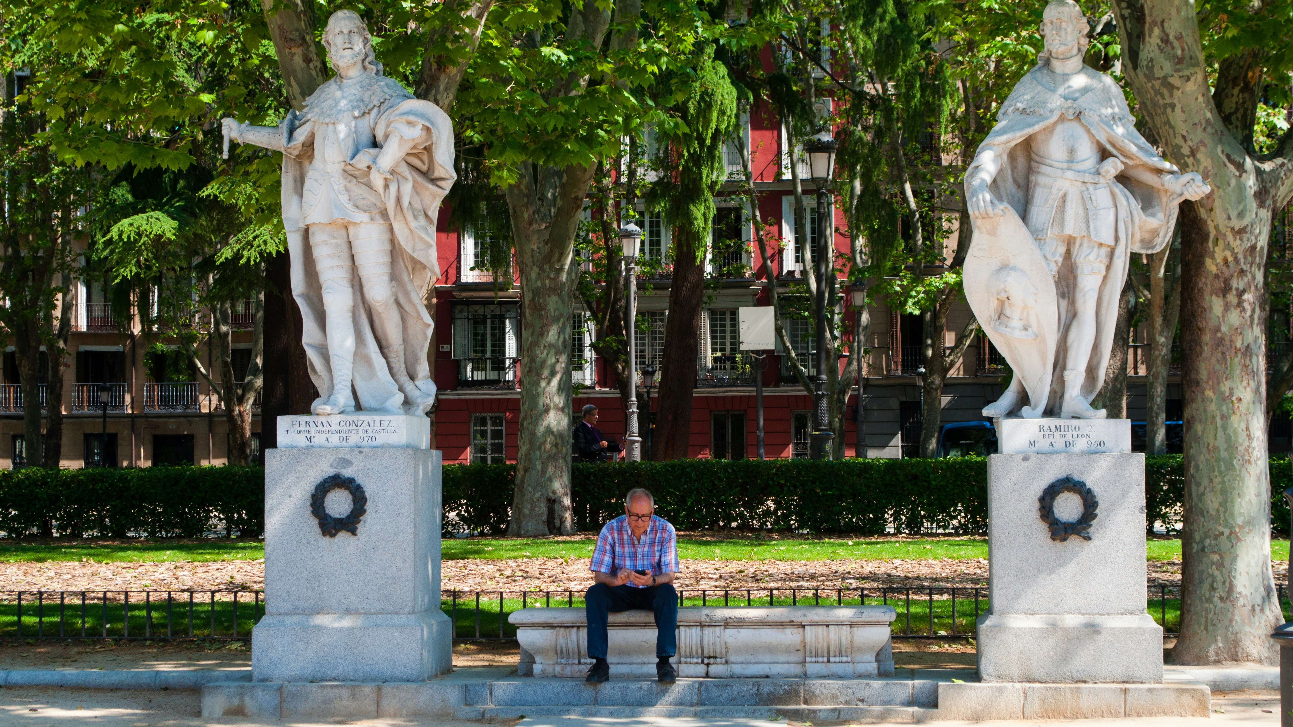 a man sitting on a bench next to two statues