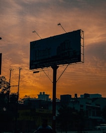 Outdoor billboard installation on an urban street corner at sunset.