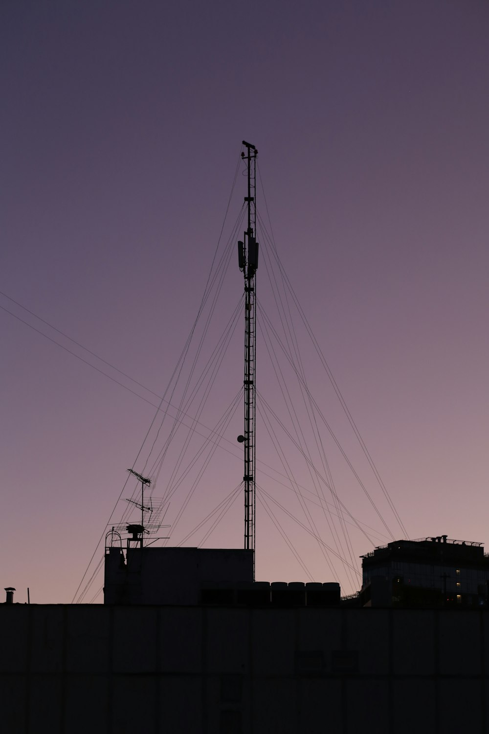 the silhouette of a building with a radio tower in the background
