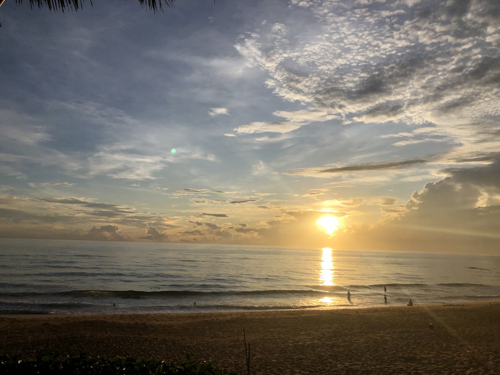 the sun is setting over the ocean on the beach