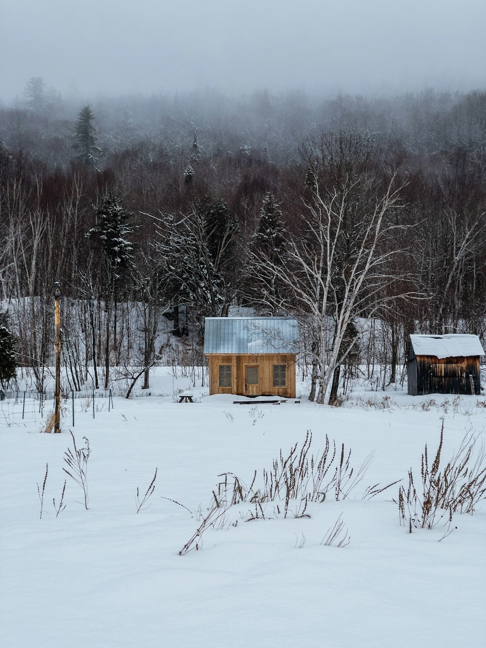 a small cabin in the middle of a snowy field