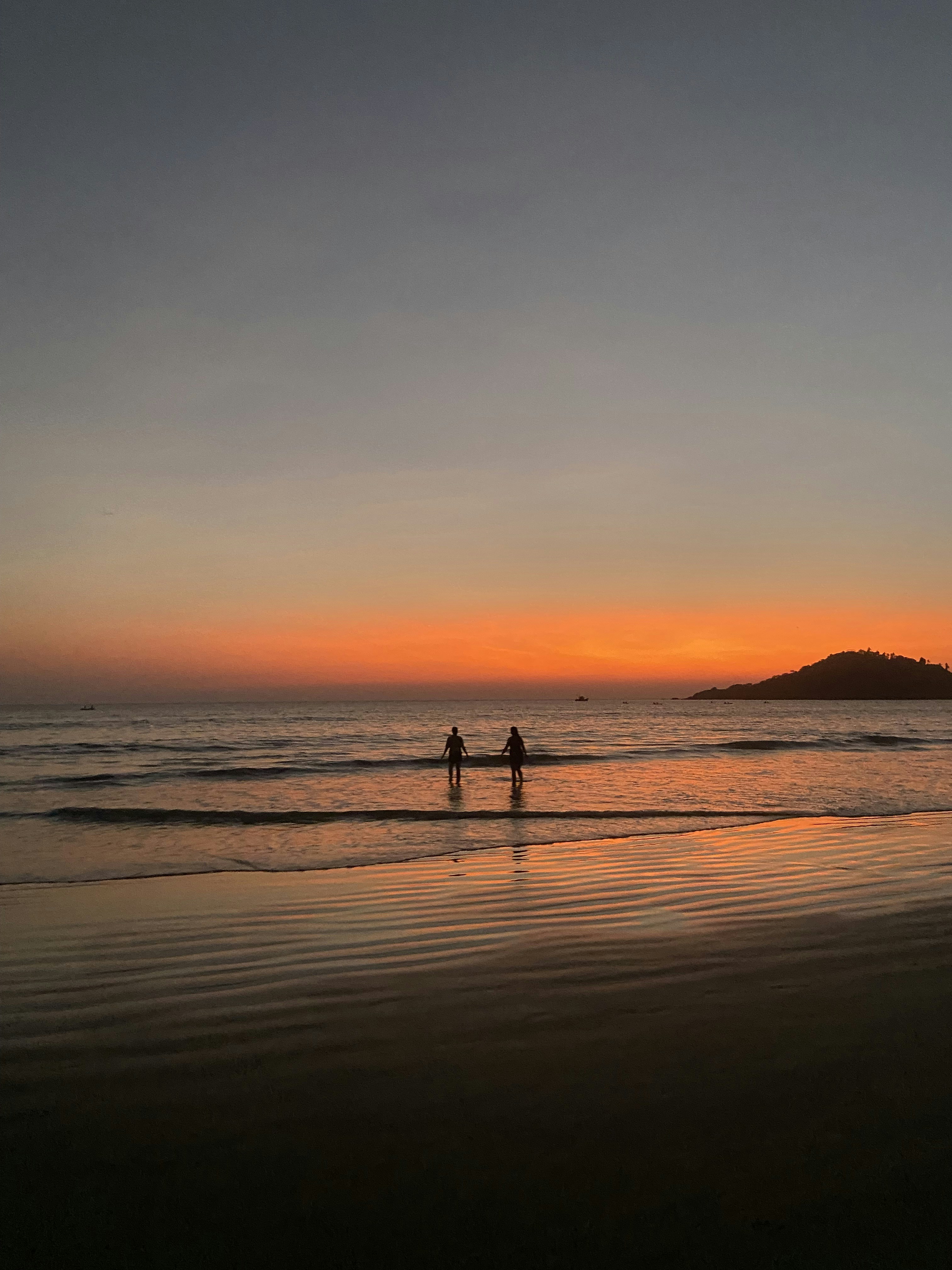 a couple of people standing on top of a sandy beach