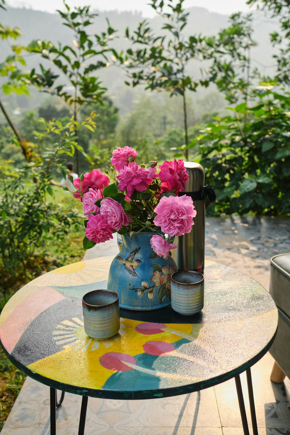 a blue vase with pink flowers on a table