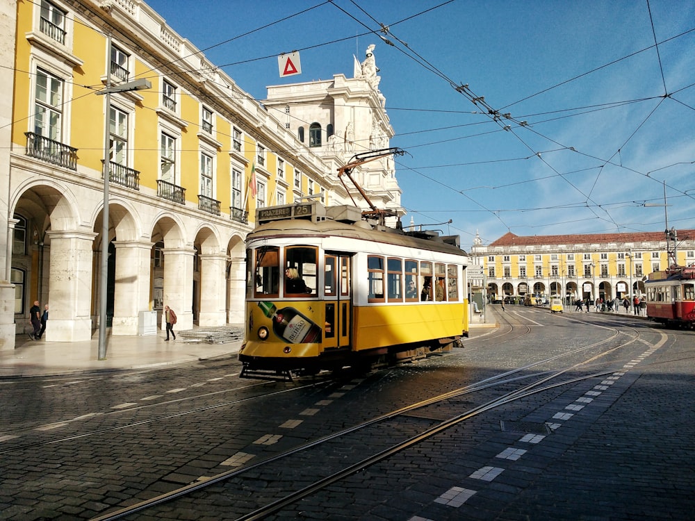 a yellow and white trolley on a city street