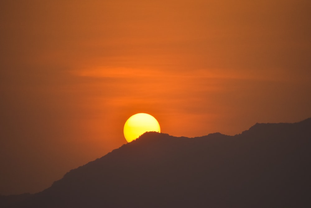 the sun is setting over a mountain range