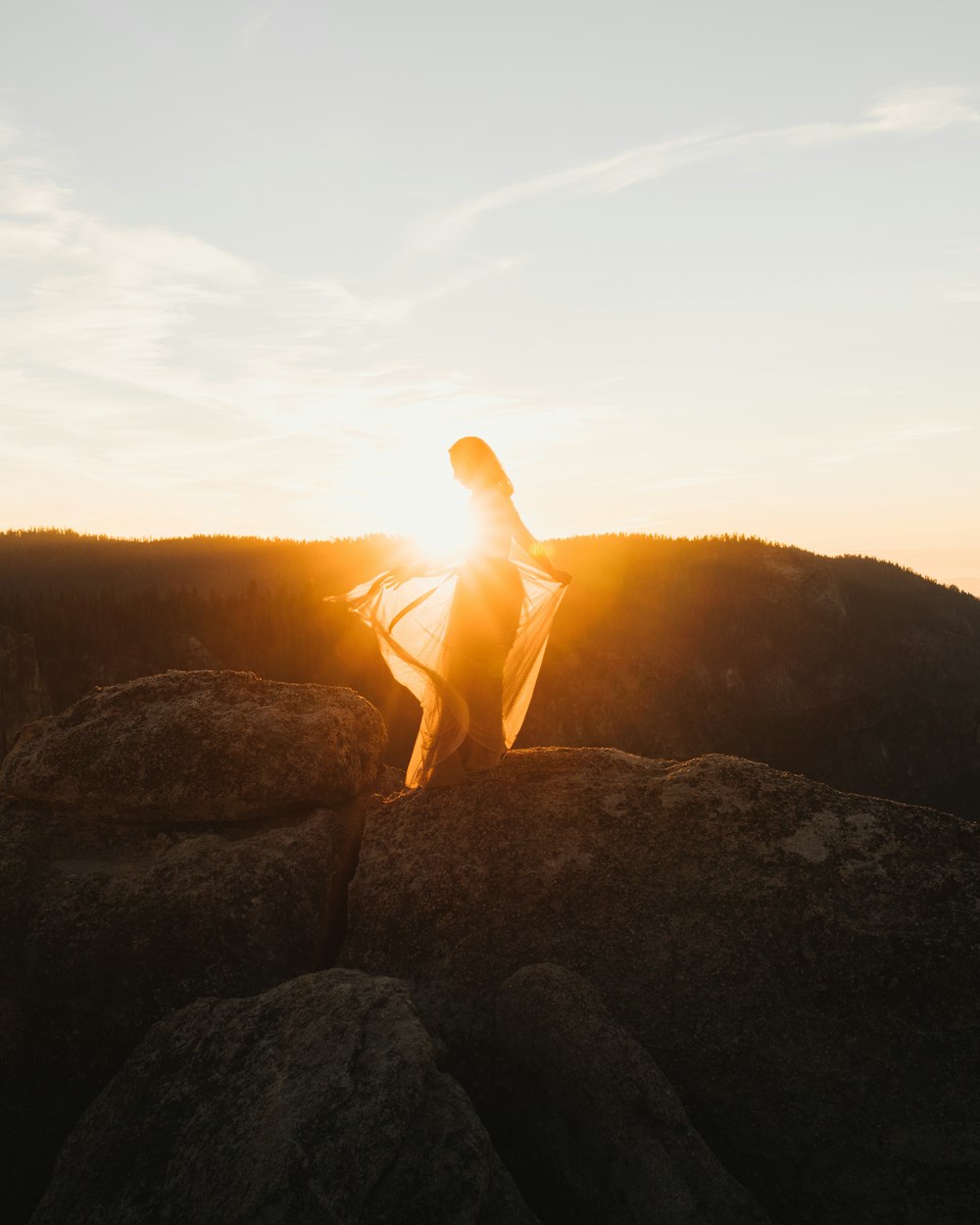 a woman standing on top of a large rock