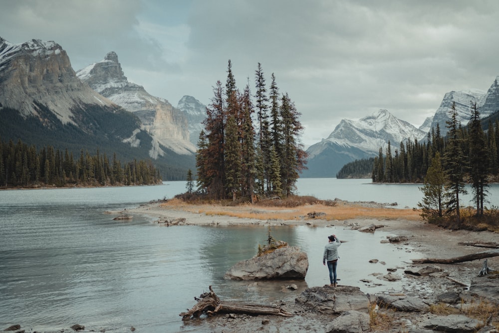 a man standing on a rocky shore next to a body of water