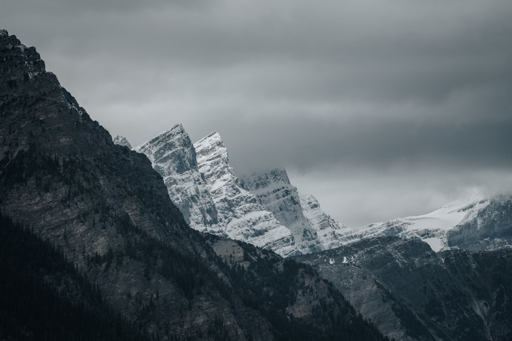 a mountain range covered in snow under a cloudy sky