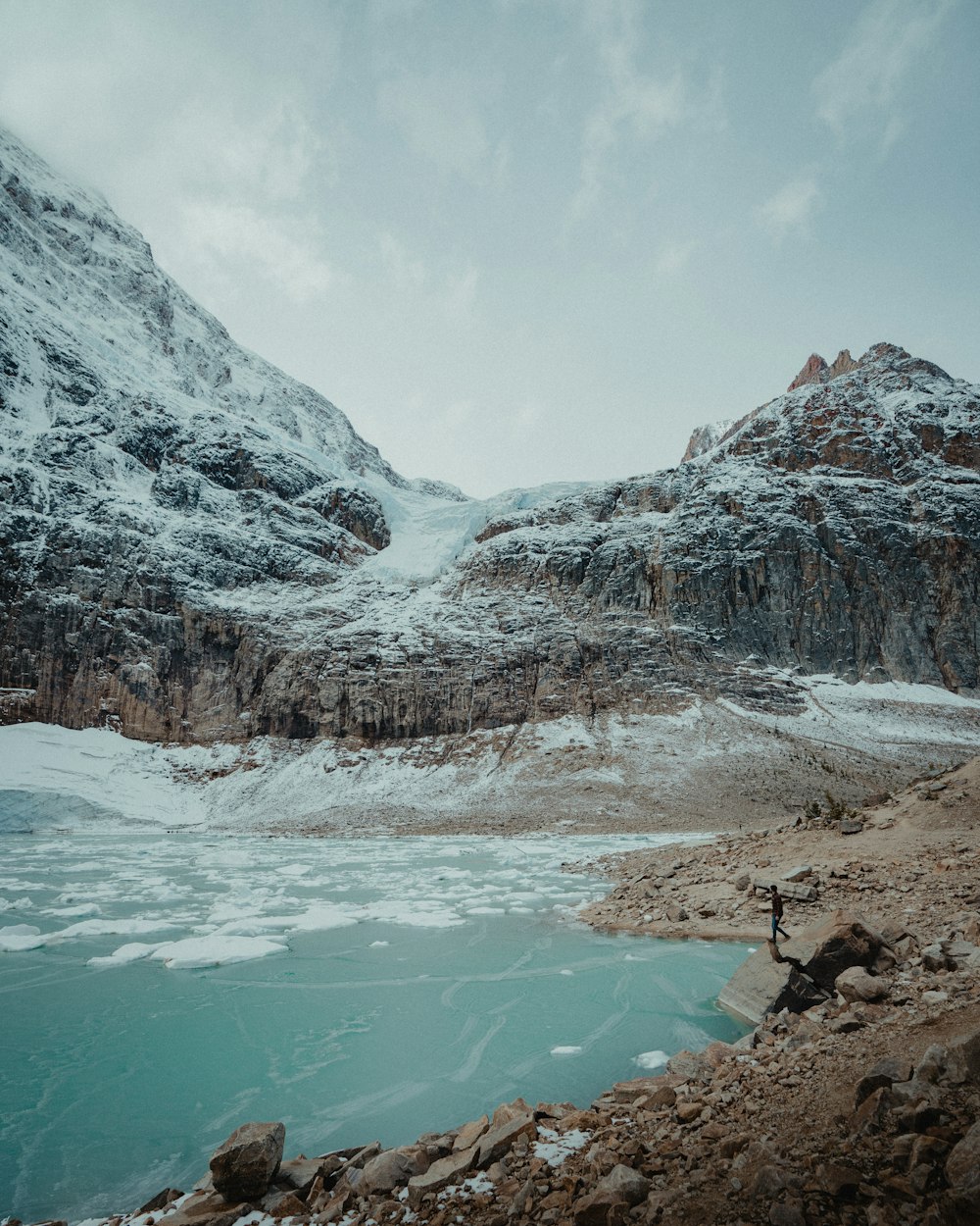 a snowy mountain with a lake in the foreground