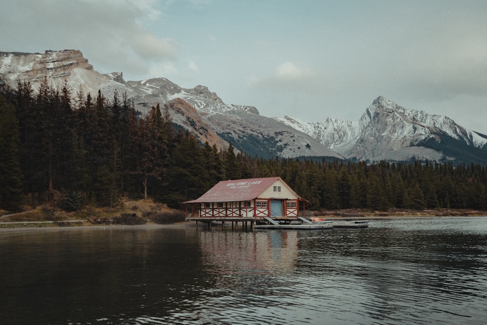 a small house on a lake with mountains in the background