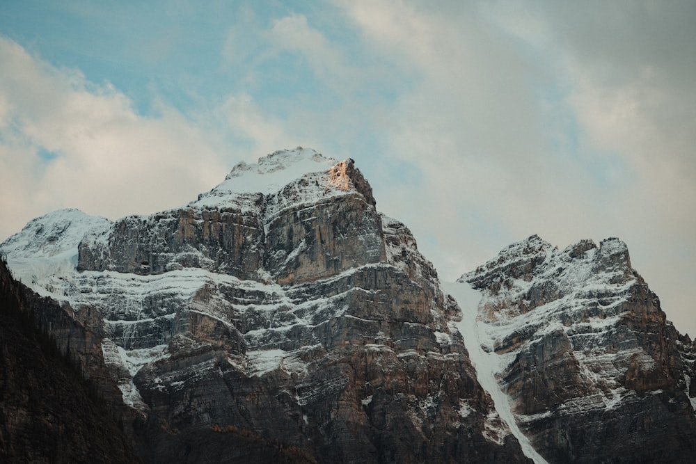 a snowy mountain with a few clouds in the sky